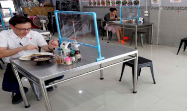 Customers eat lunch behind plastic shields in Bangkok