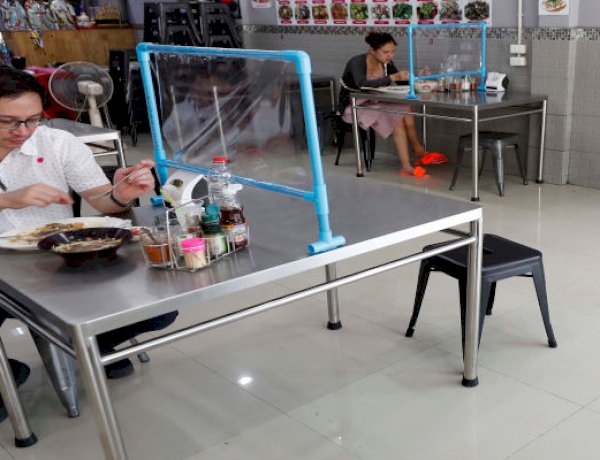 Customers eat lunch behind plastic shields in Bangkok